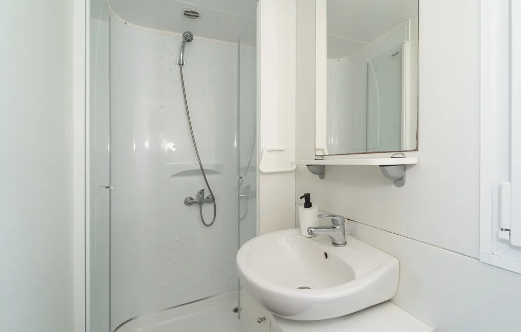 Un baño con ducha, lavabo y espejo de pared.