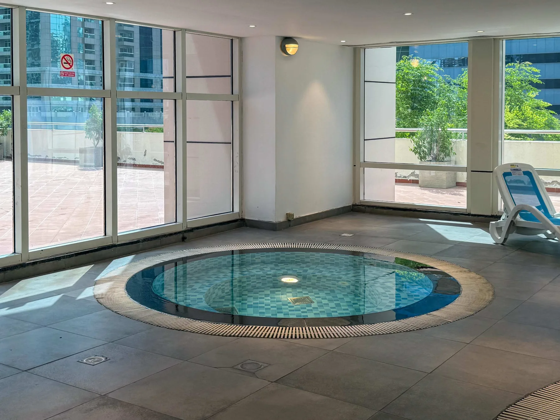 An indoor pool area with a circular pool beside large windows.