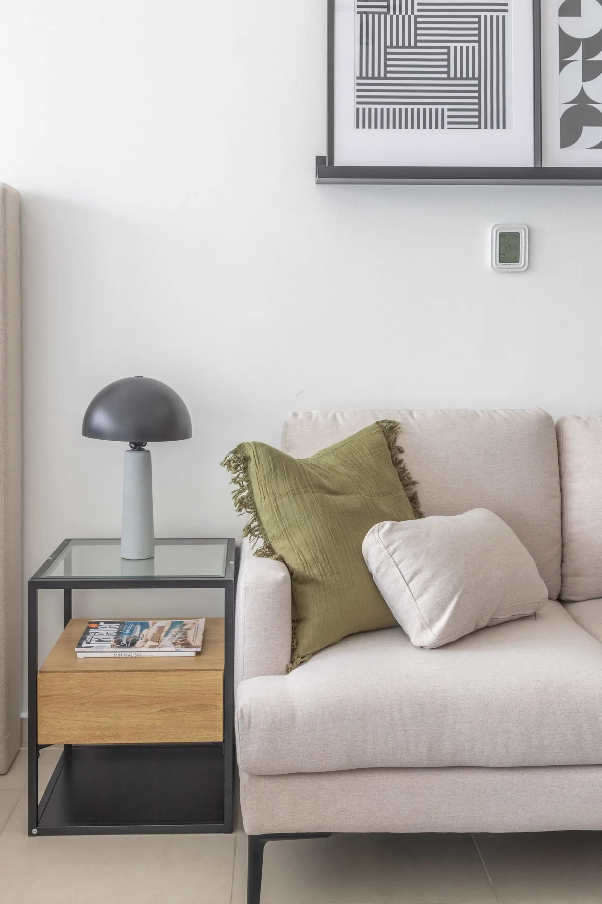 A living room with light-colored seating, a side table, and a table lamp.
