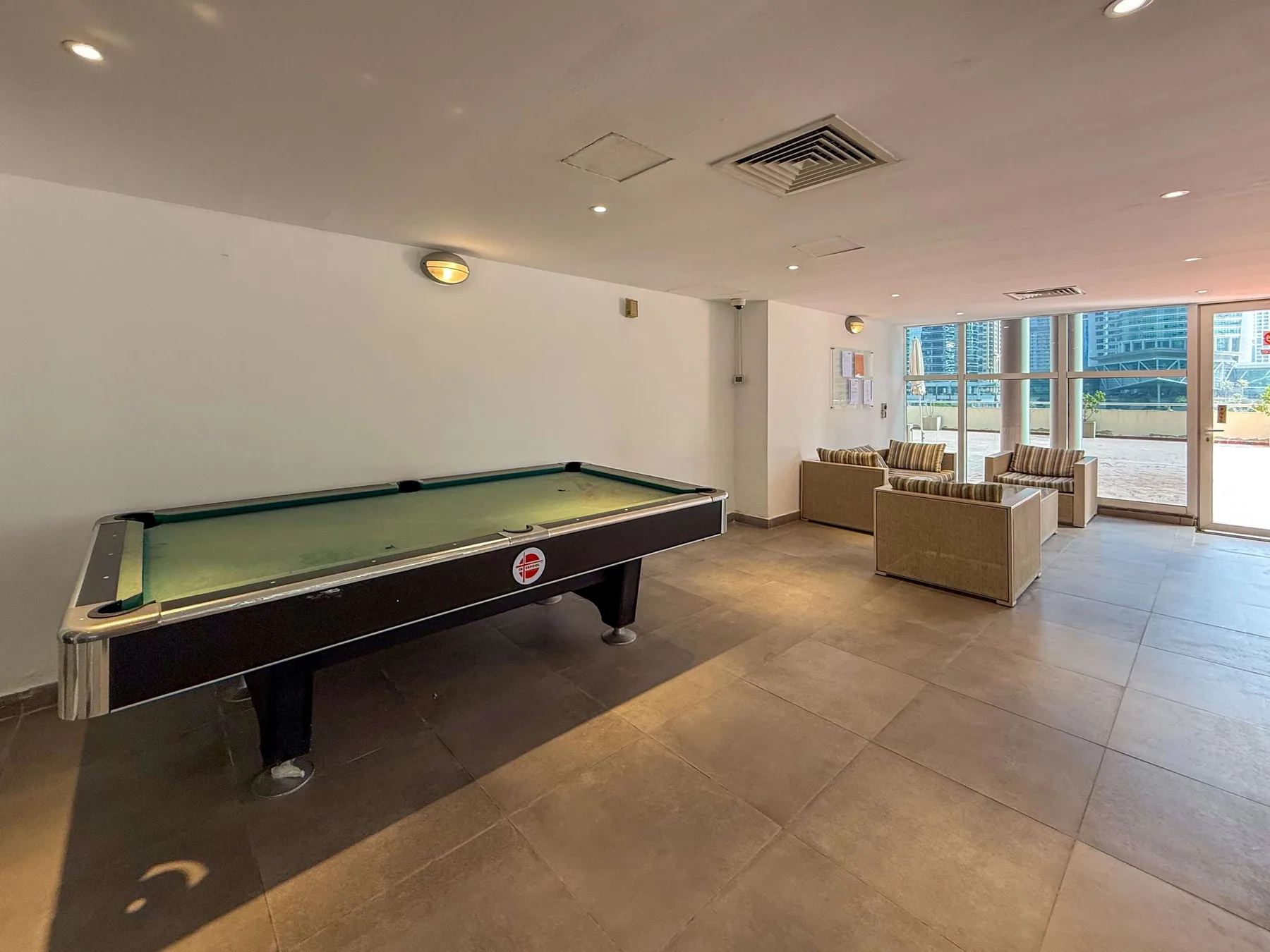 A recreation room with a pool table and seating by the windows.
