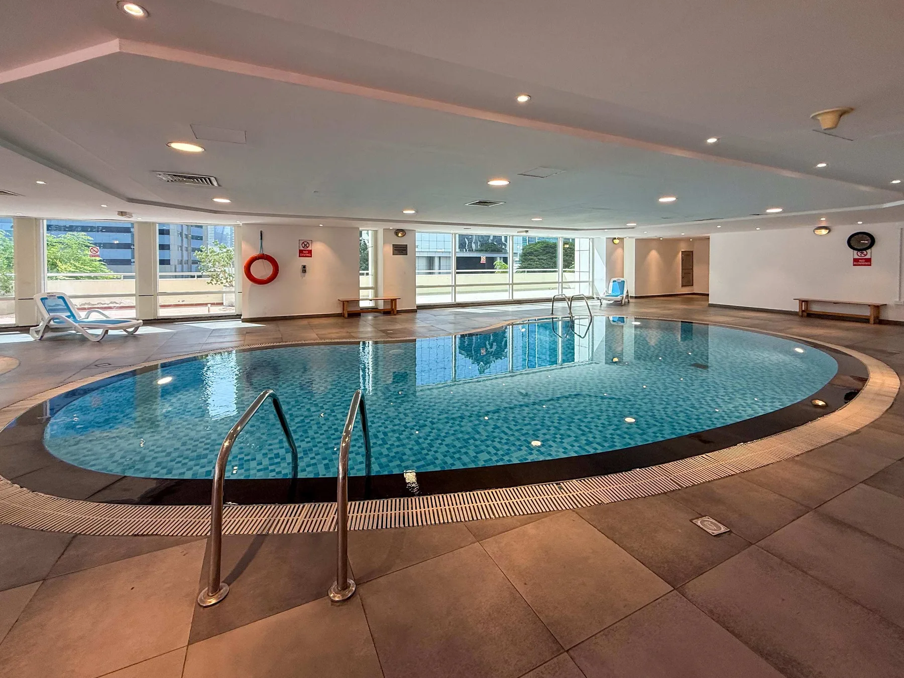 An indoor swimming pool with large windows and tiled flooring.