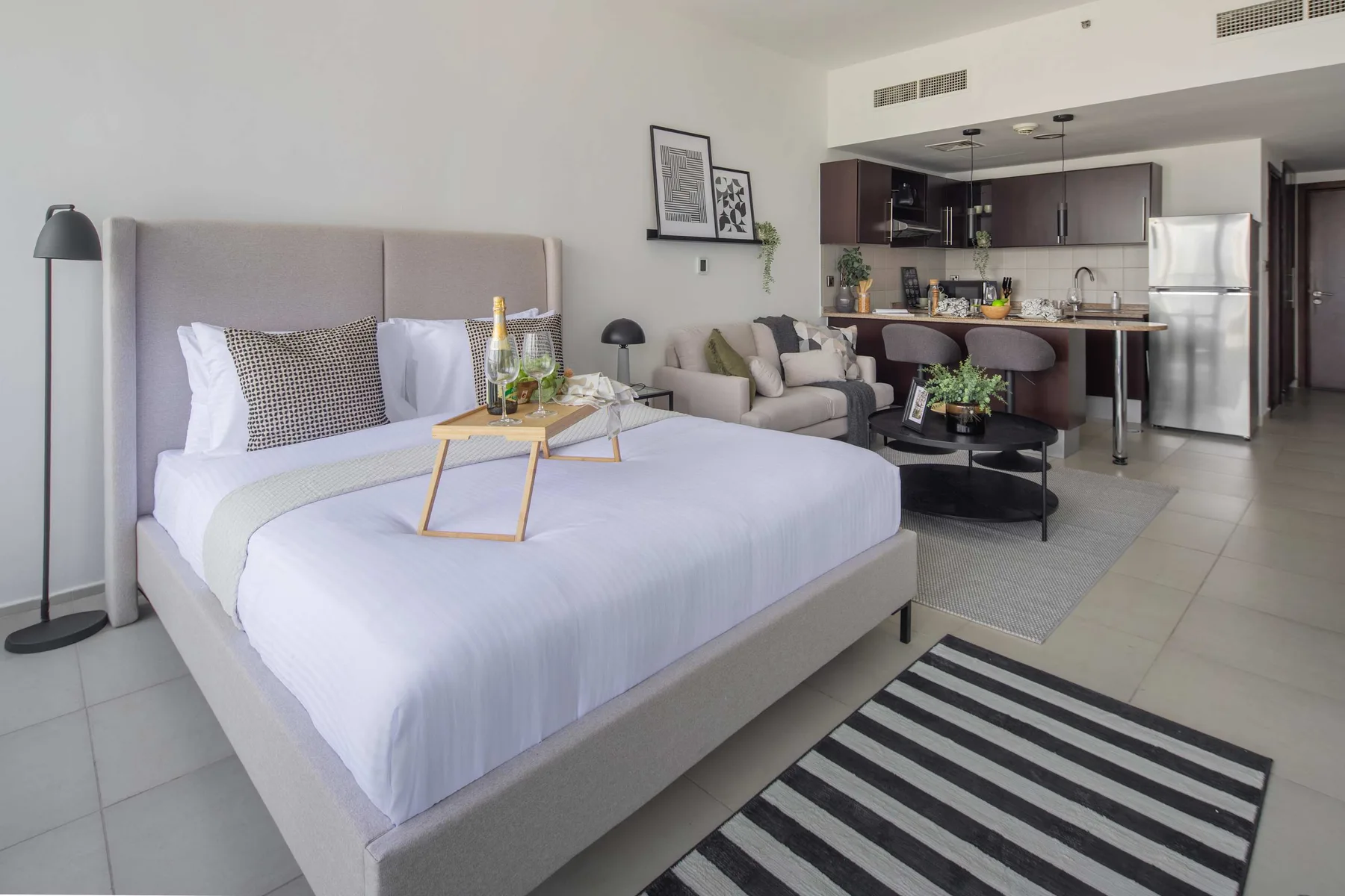 A bedroom and living area open into a compact kitchen with a breakfast bar.