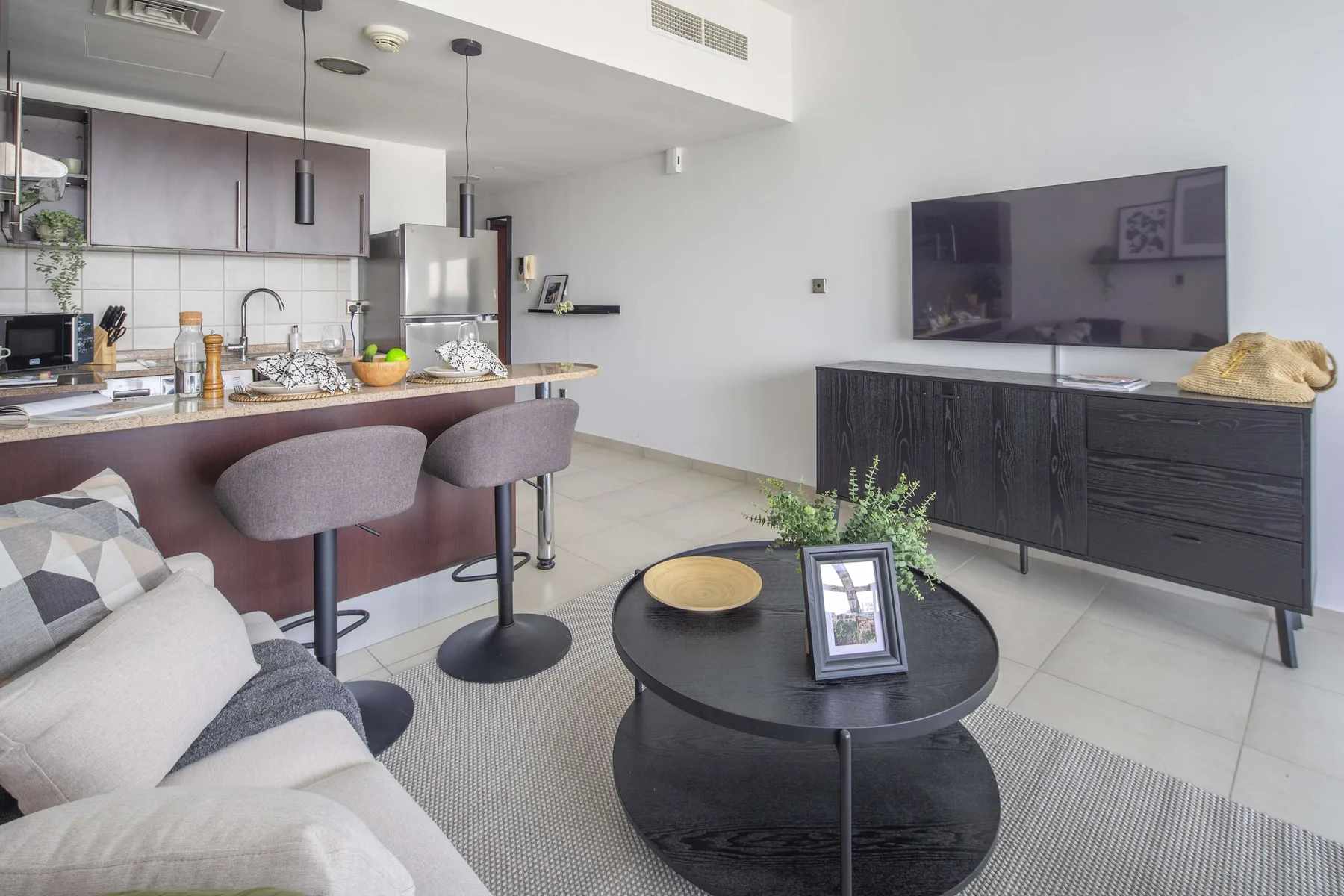 A living room opens onto a kitchen, with seating facing a television.