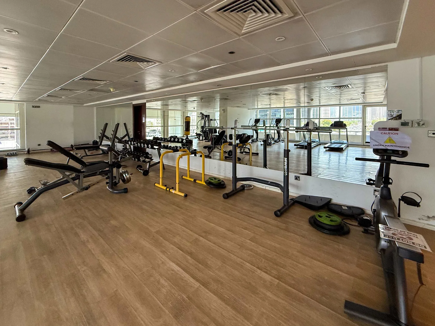 A spacious gym with exercise bikes, weight equipment, and large windows.