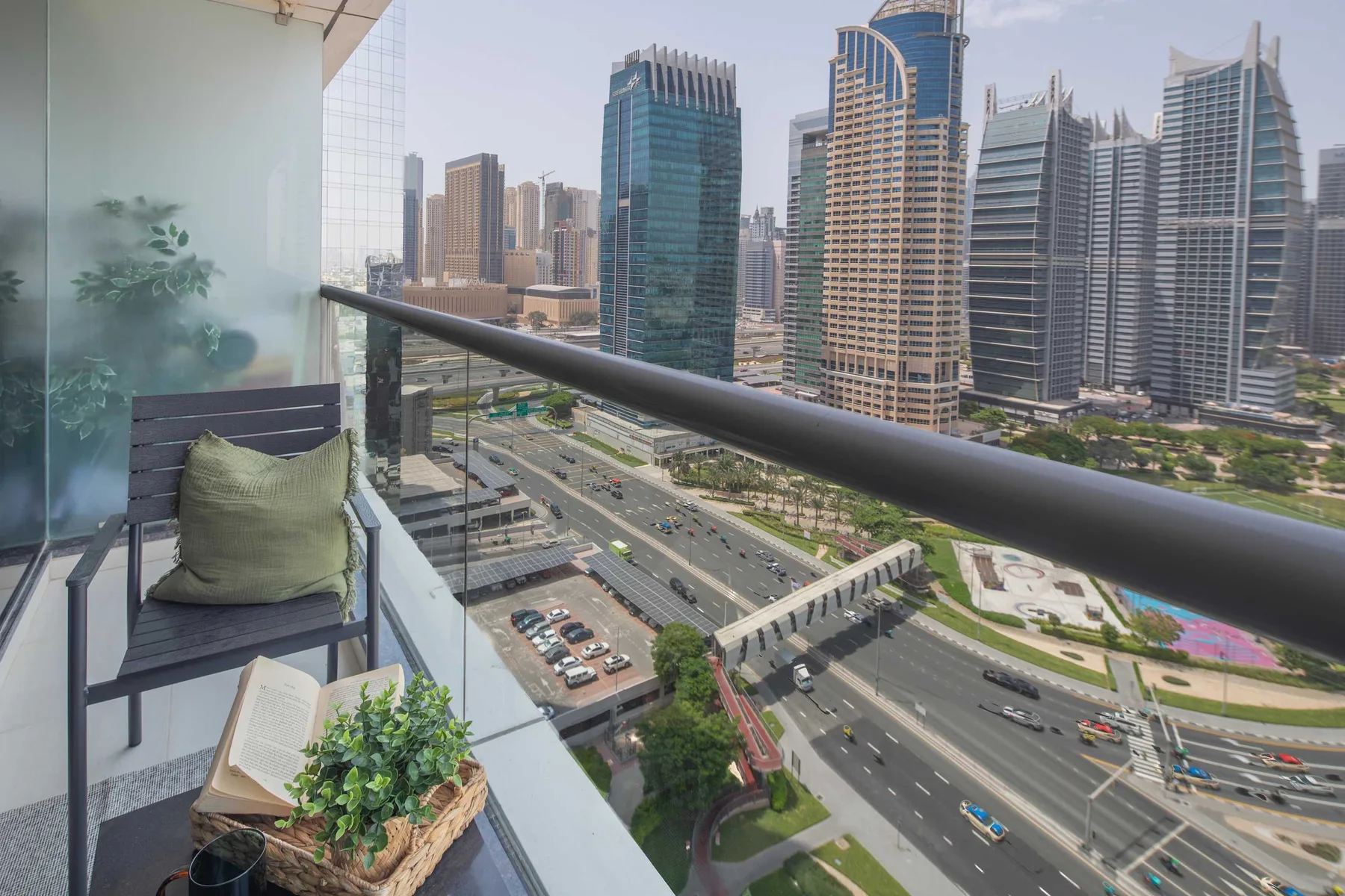 A balcony overlooks a busy road and a cluster of modern high-rise buildings.