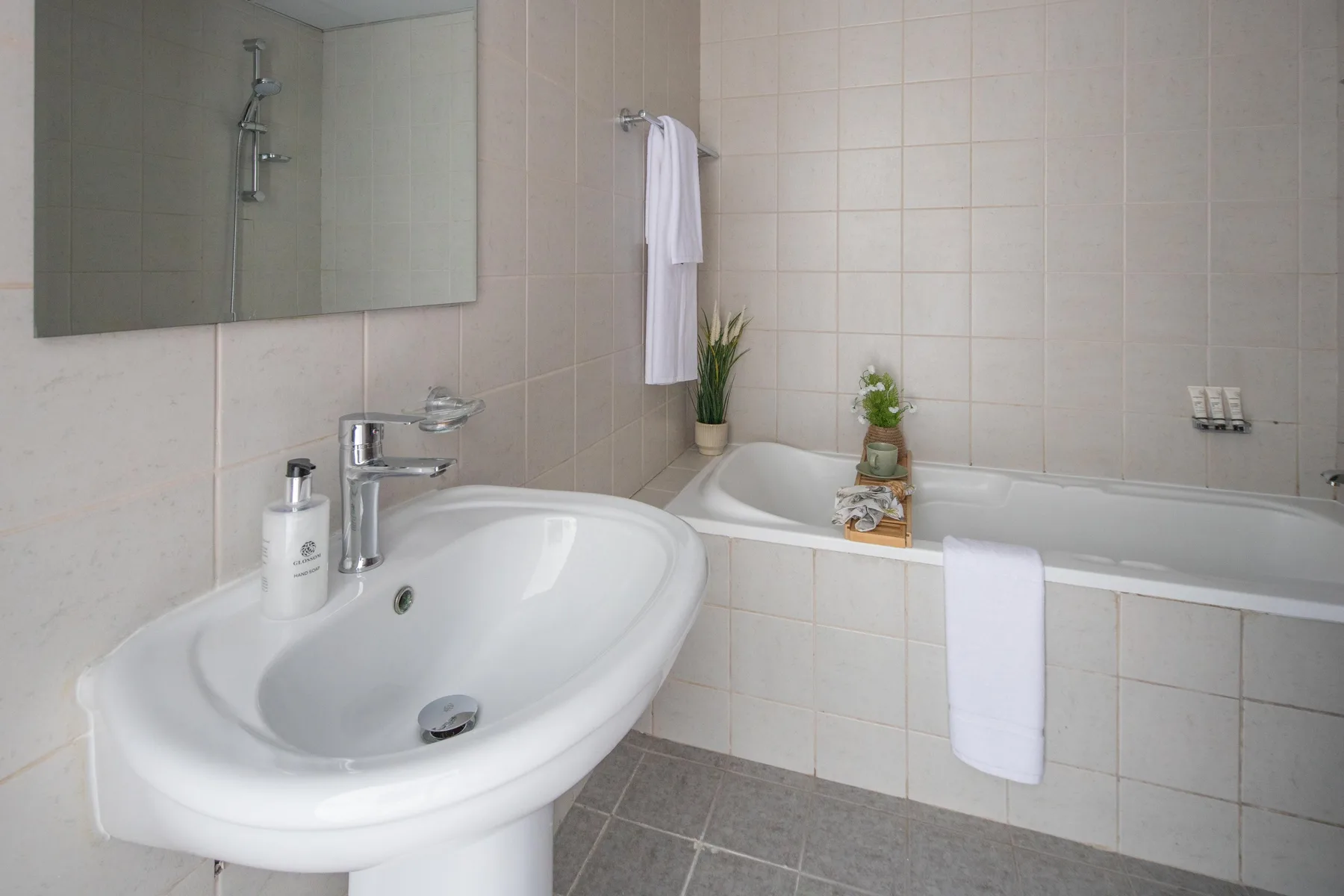 A tiled bathroom with a sink beside a bathtub.