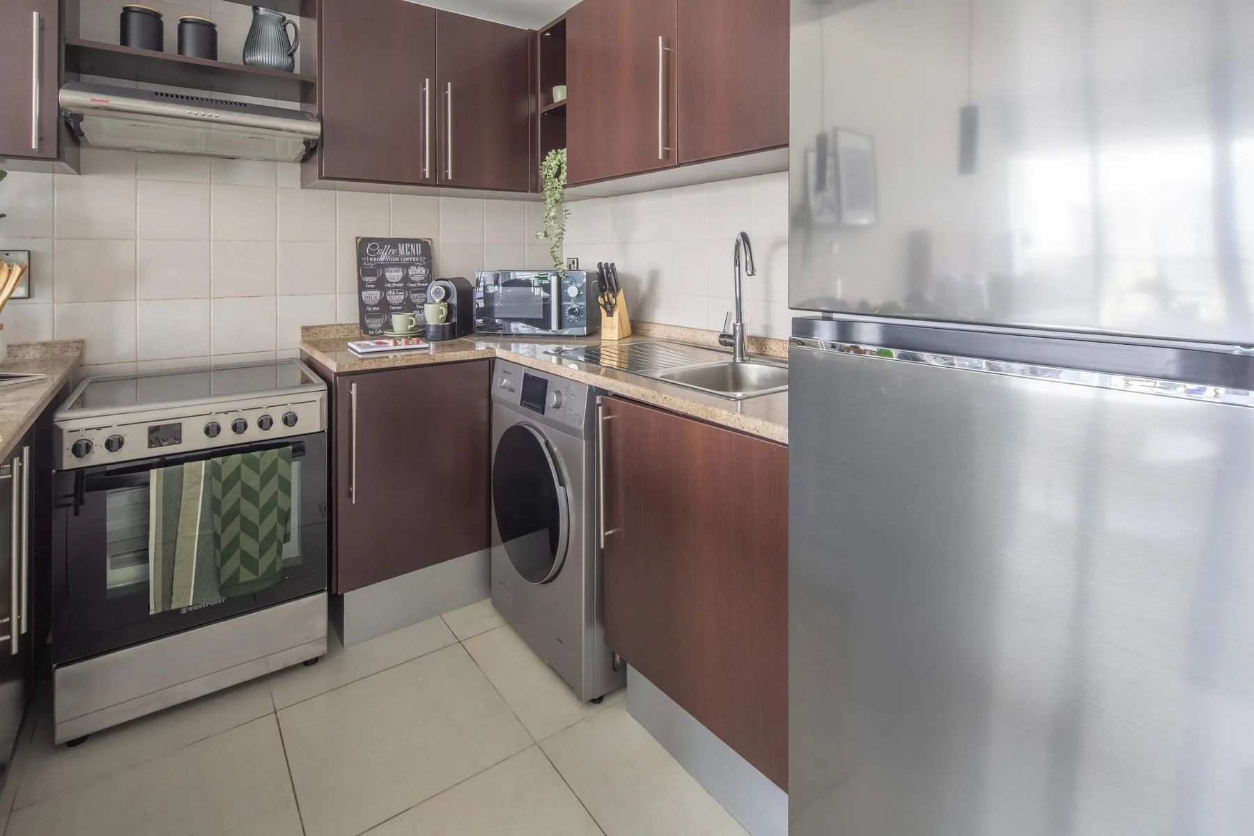 A compact kitchen with dark cabinets, a stove, and a washing machine.
