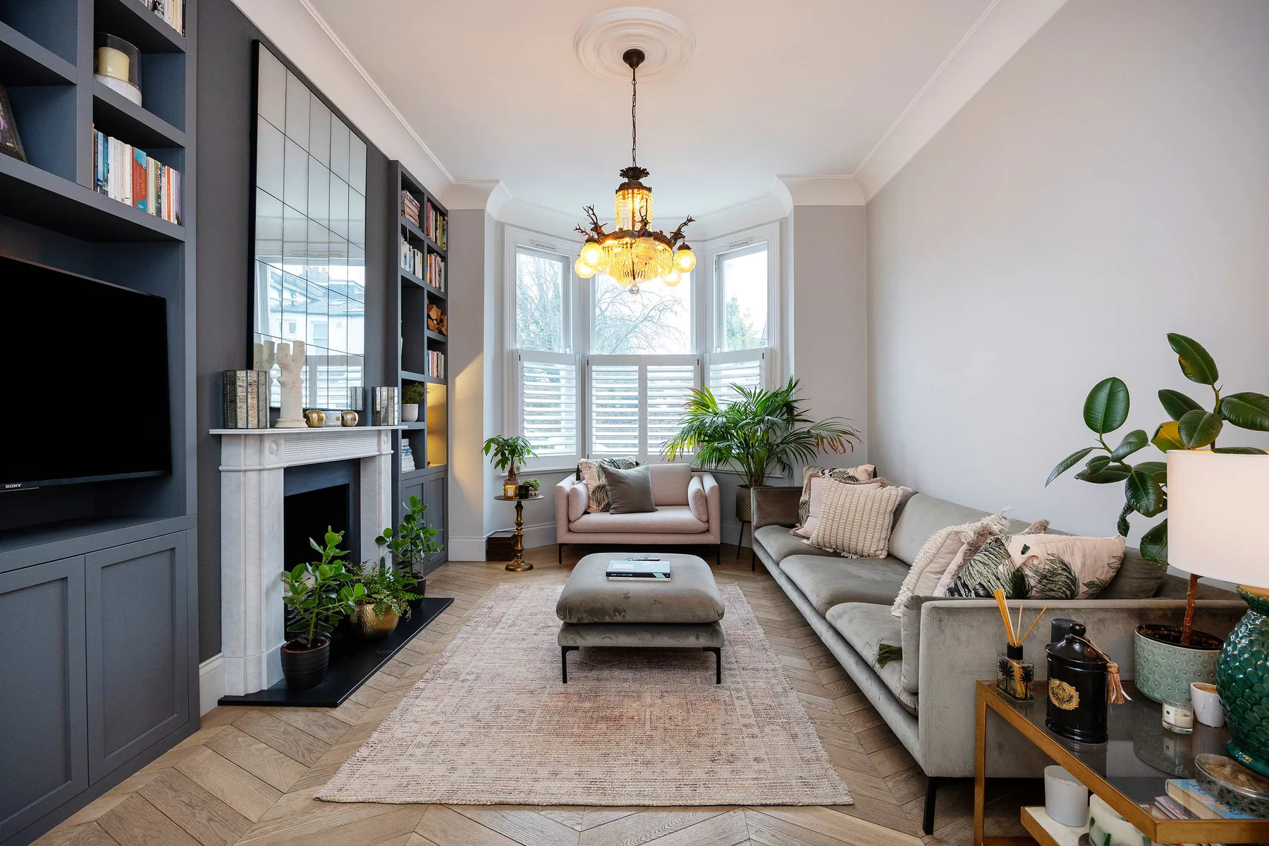 A bright living room with seating around a coffee table and windows at the far end.