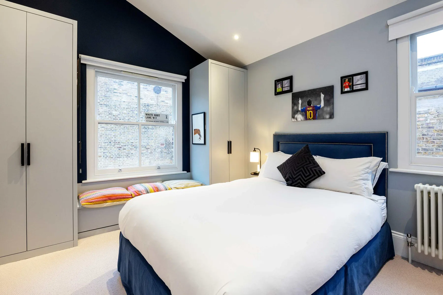 A bedroom with a large bed, built-in cabinets, and windows.