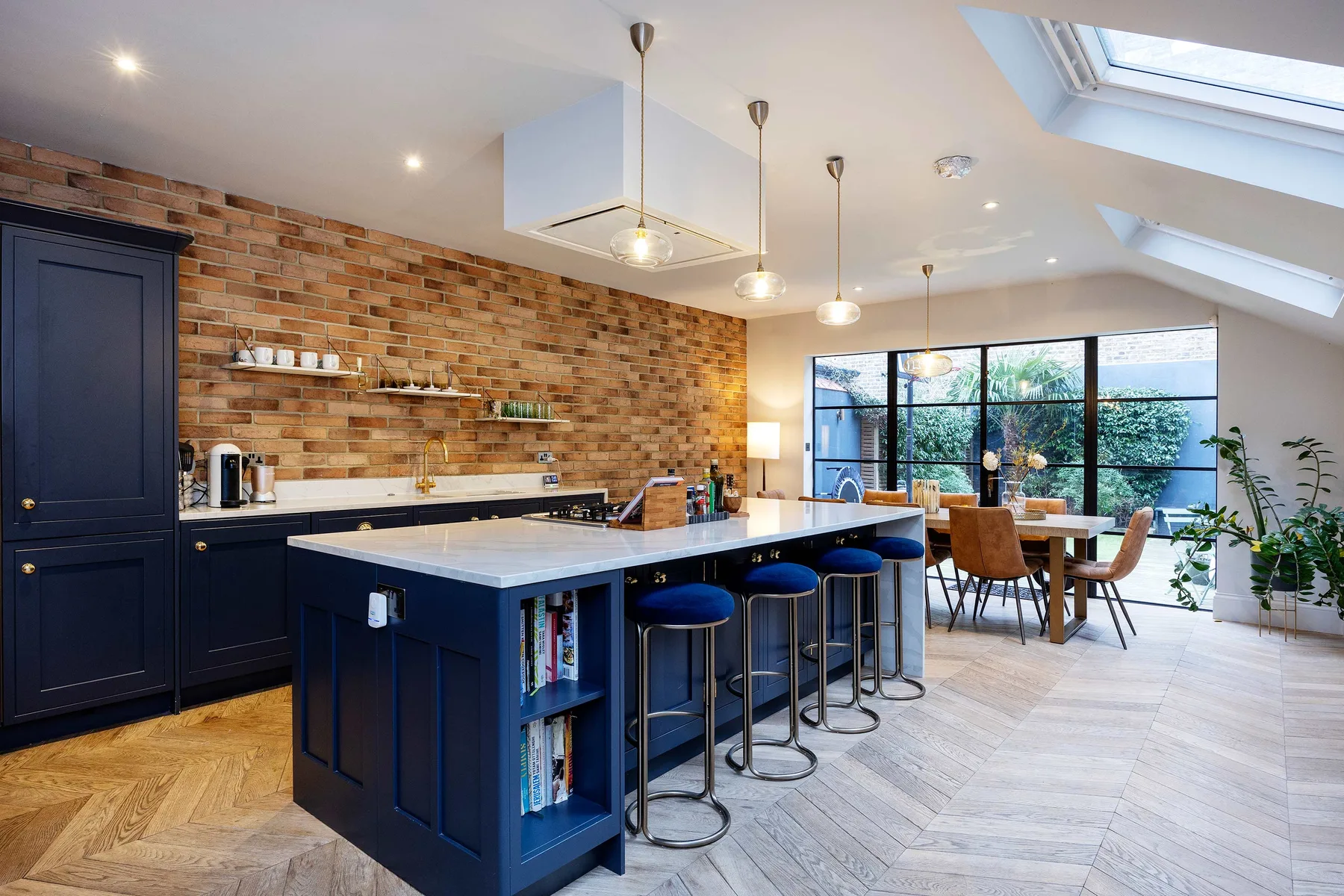 A spacious kitchen with a dark island, bar seating, and large windows.