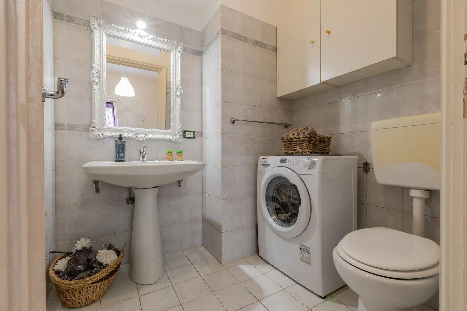 Un baño con azulejos, lavabo, lavadora e inodoro.