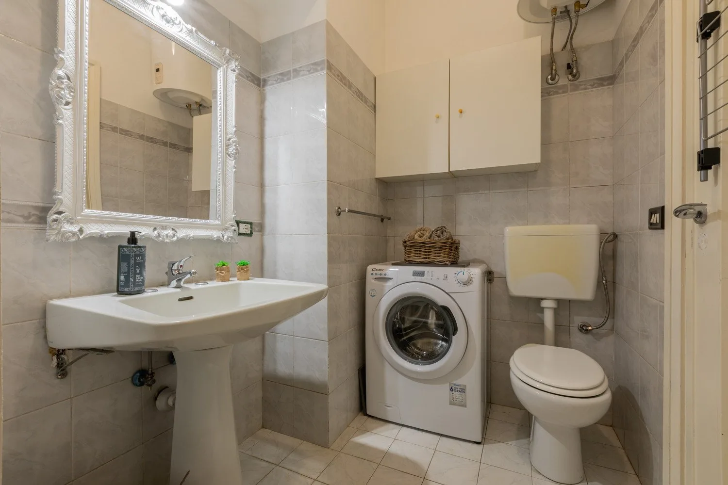 Un baño con azulejos, lavabo, lavadora e inodoro.
