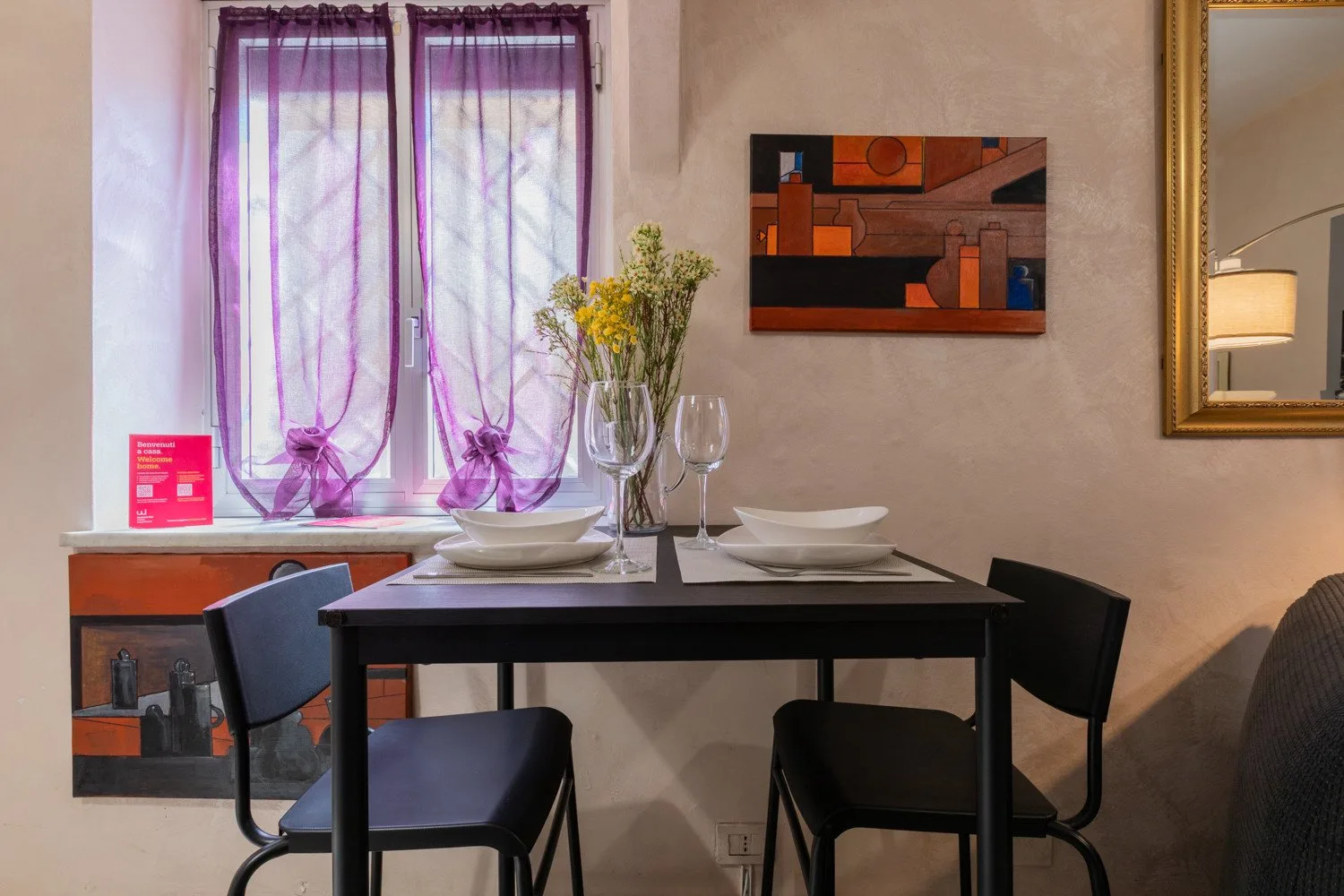 Comedor con una mesa puesta bajo un cuadro abstracto colorido.