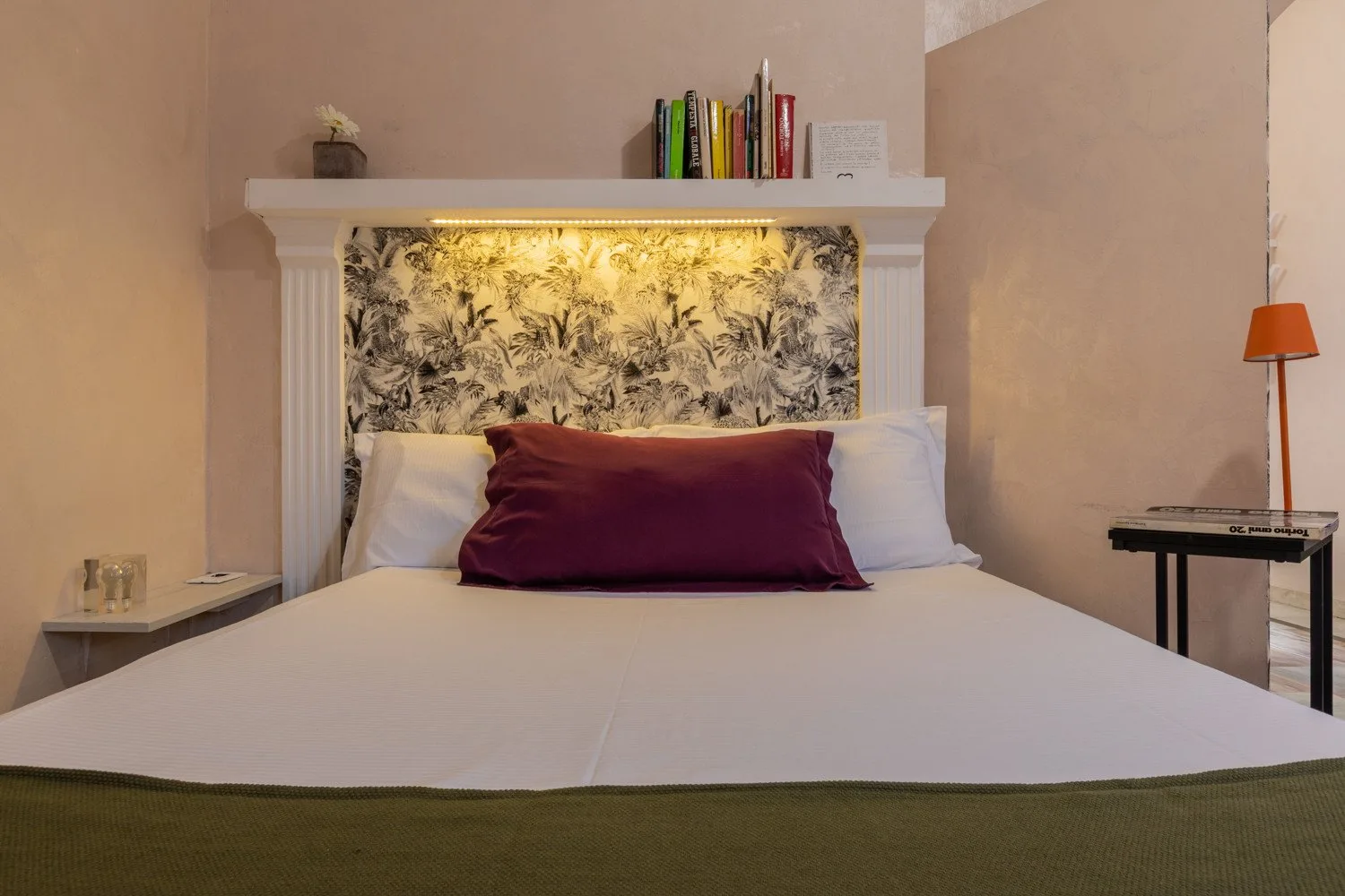 Un dormitorio con una cama bien tendida y un cabecero estampado.