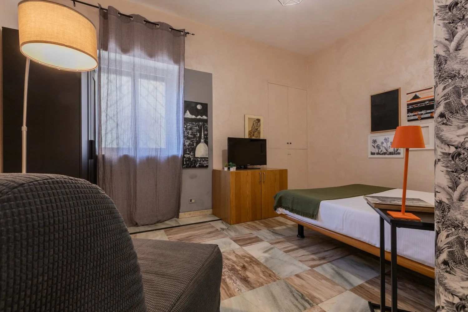 Un dormitorio con una cama, un televisor sobre un mueble de madera y una zona de estar.