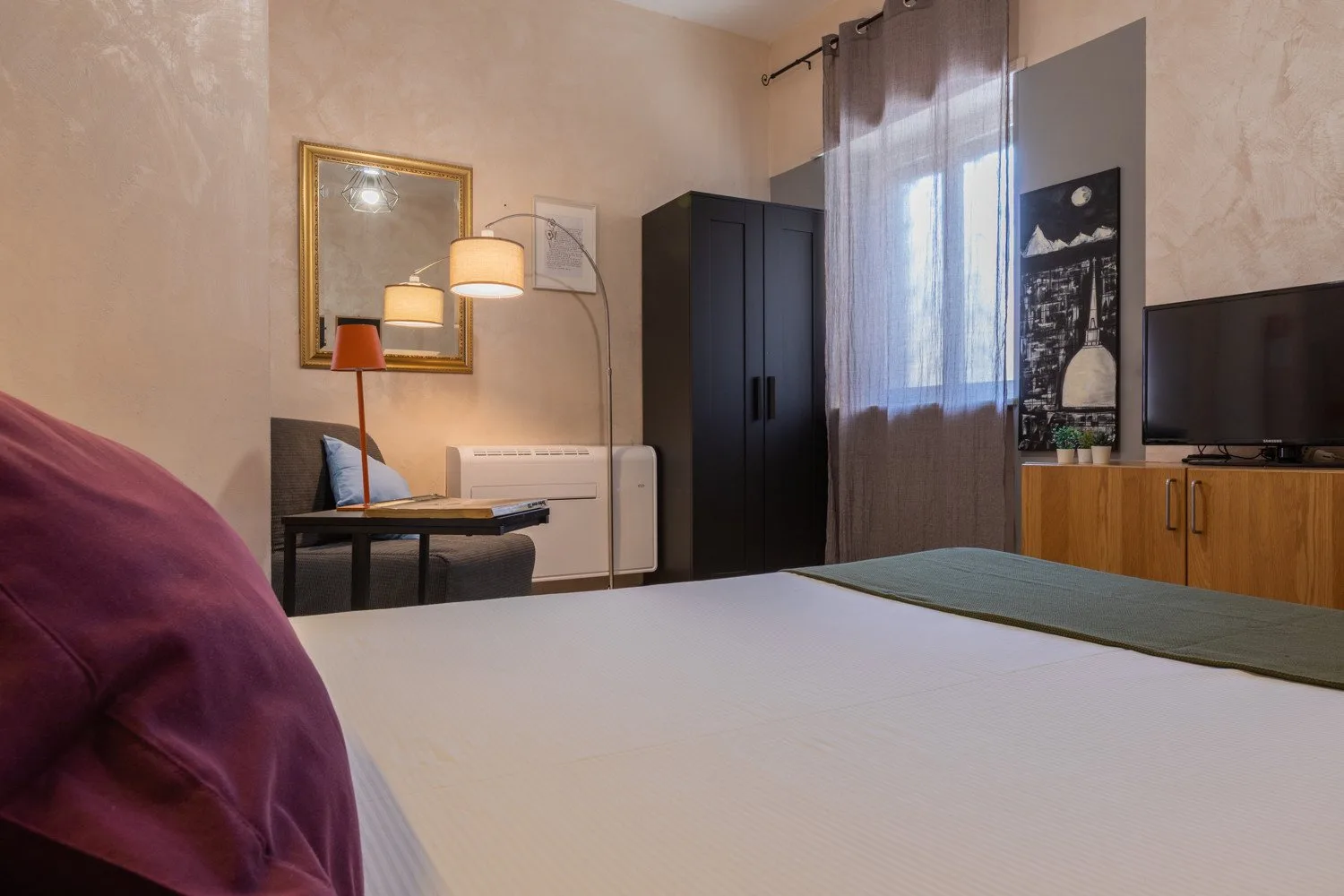 Un dormitorio con cama, mesa auxiliar y armario.