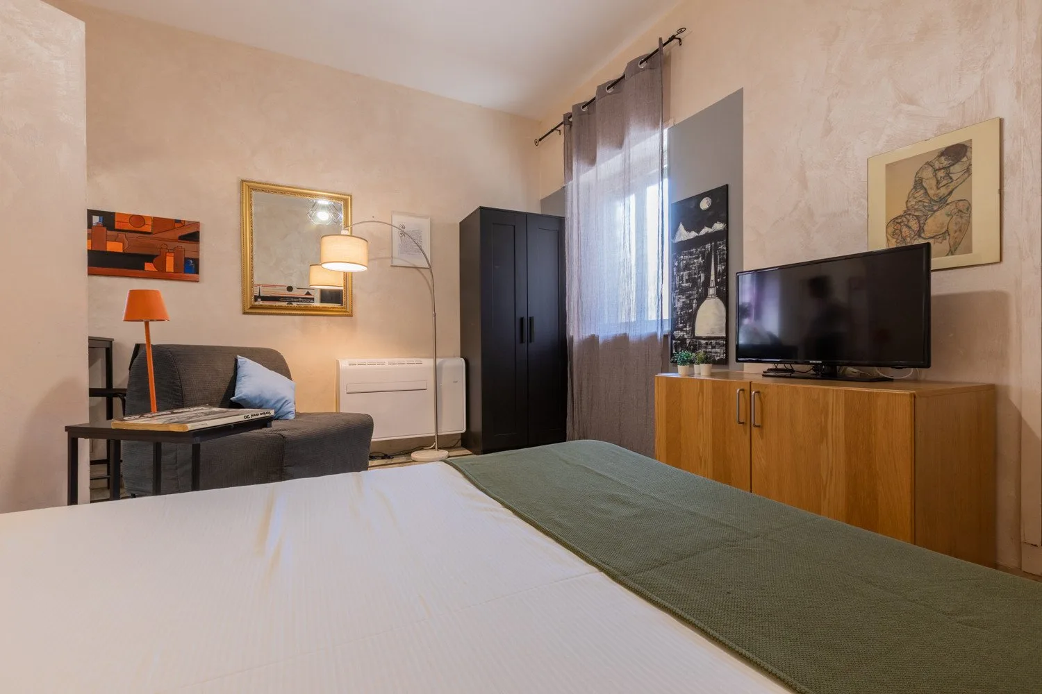Un dormitorio con una cama, una zona de estar y un televisor sobre un mueble de madera.
