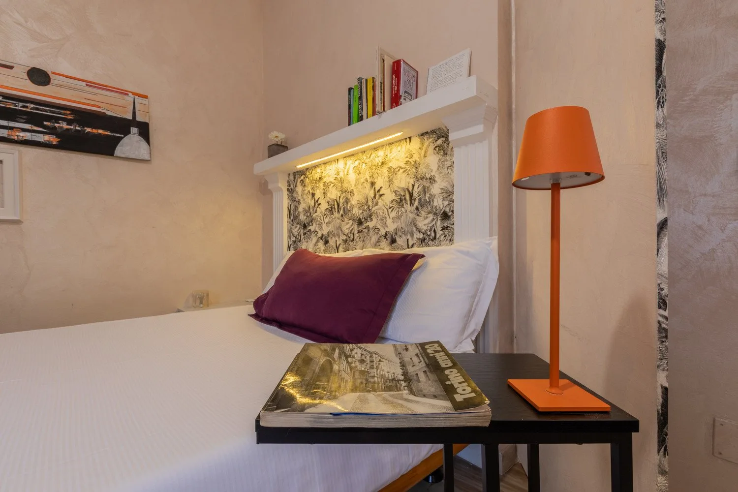Un dormitorio con una cama tendida y una lámpara de pie naranja al lado.