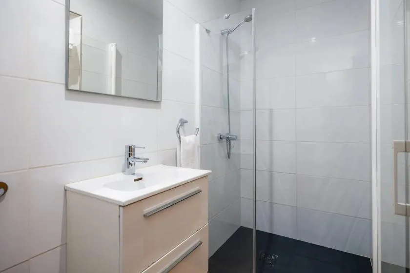 Un baño luminoso con lavabo y ducha de cristal.