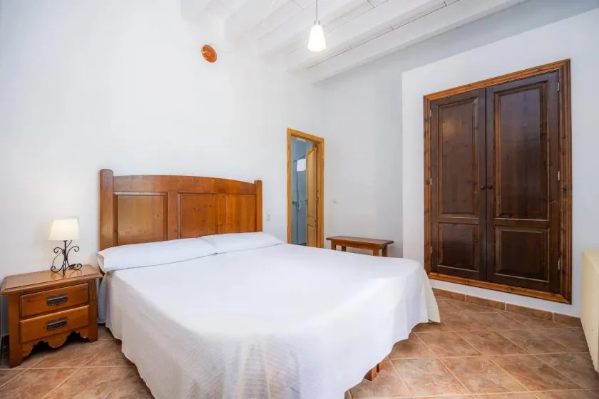 Un dormitorio con cama de madera, ropa de cama blanca y puertas de madera oscura.