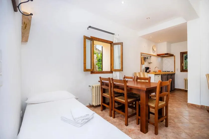Comedor con una mesa y sillas de madera junto a una ventana abierta.