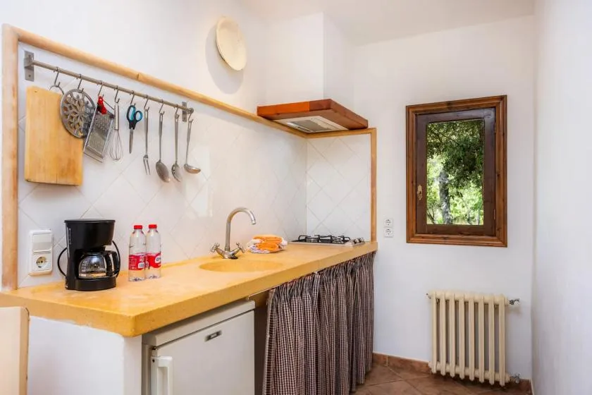Una cocina compacta con encimera, fregadero, placa de cocina y ventana.