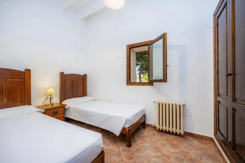 Un dormitorio luminoso con dos camas individuales y una ventana abierta.