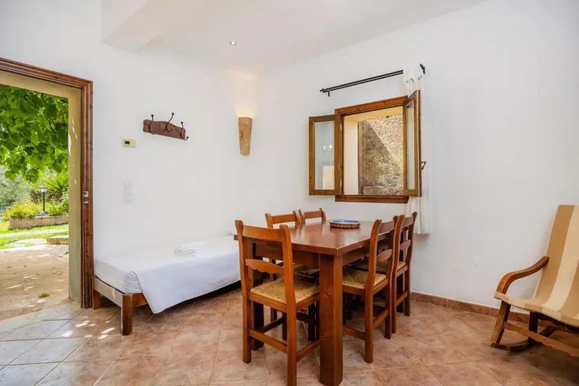 Un comedor con una mesa de madera y sillas junto a una cama individual.