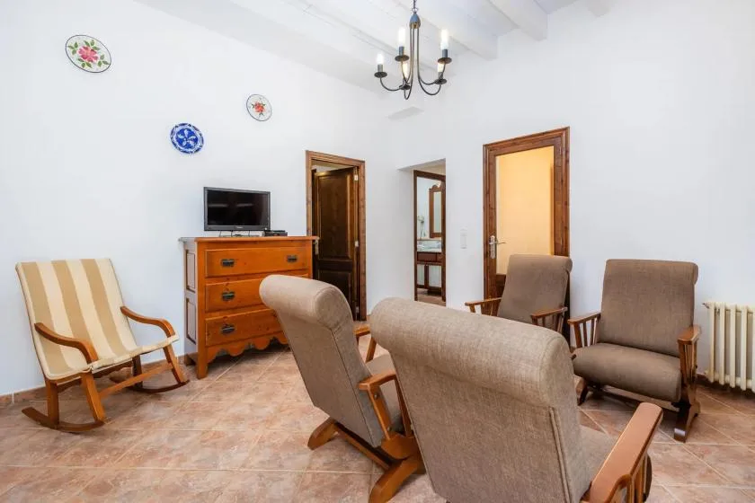 A bright sitting room with several seats and a wooden chest of drawers.