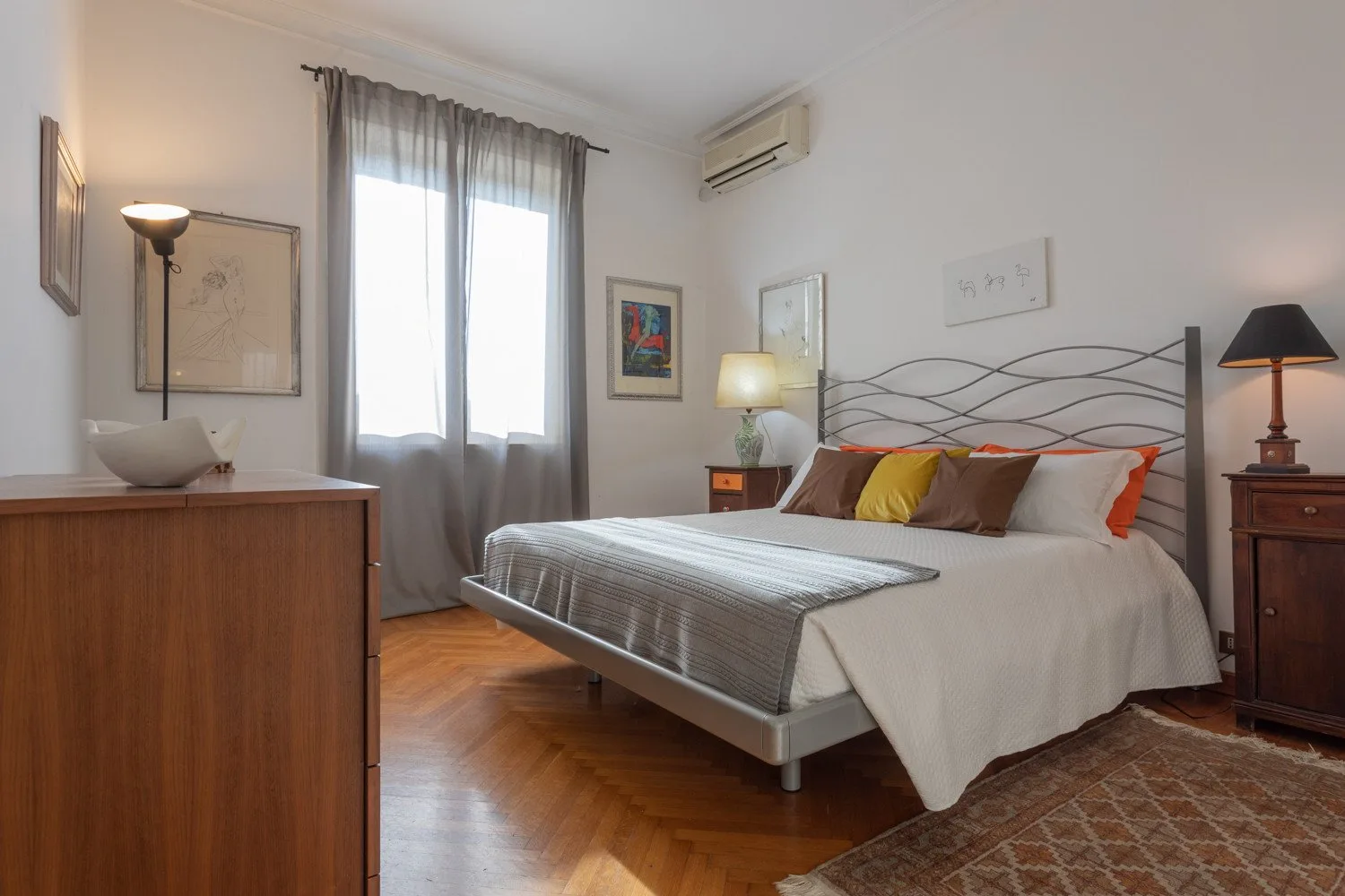 A bedroom with a double bed, bedside tables, and a window with curtains.