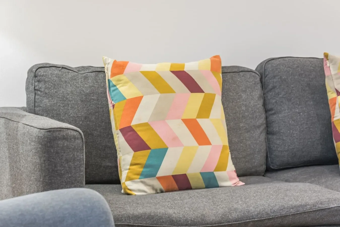 Un sofá gris con un cojín estampado de colores en una sala de estar.