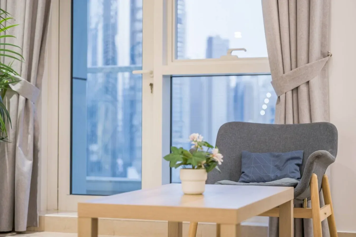Una zona de estar luminosa con una mesa, asientos acolchados y grandes ventanas.