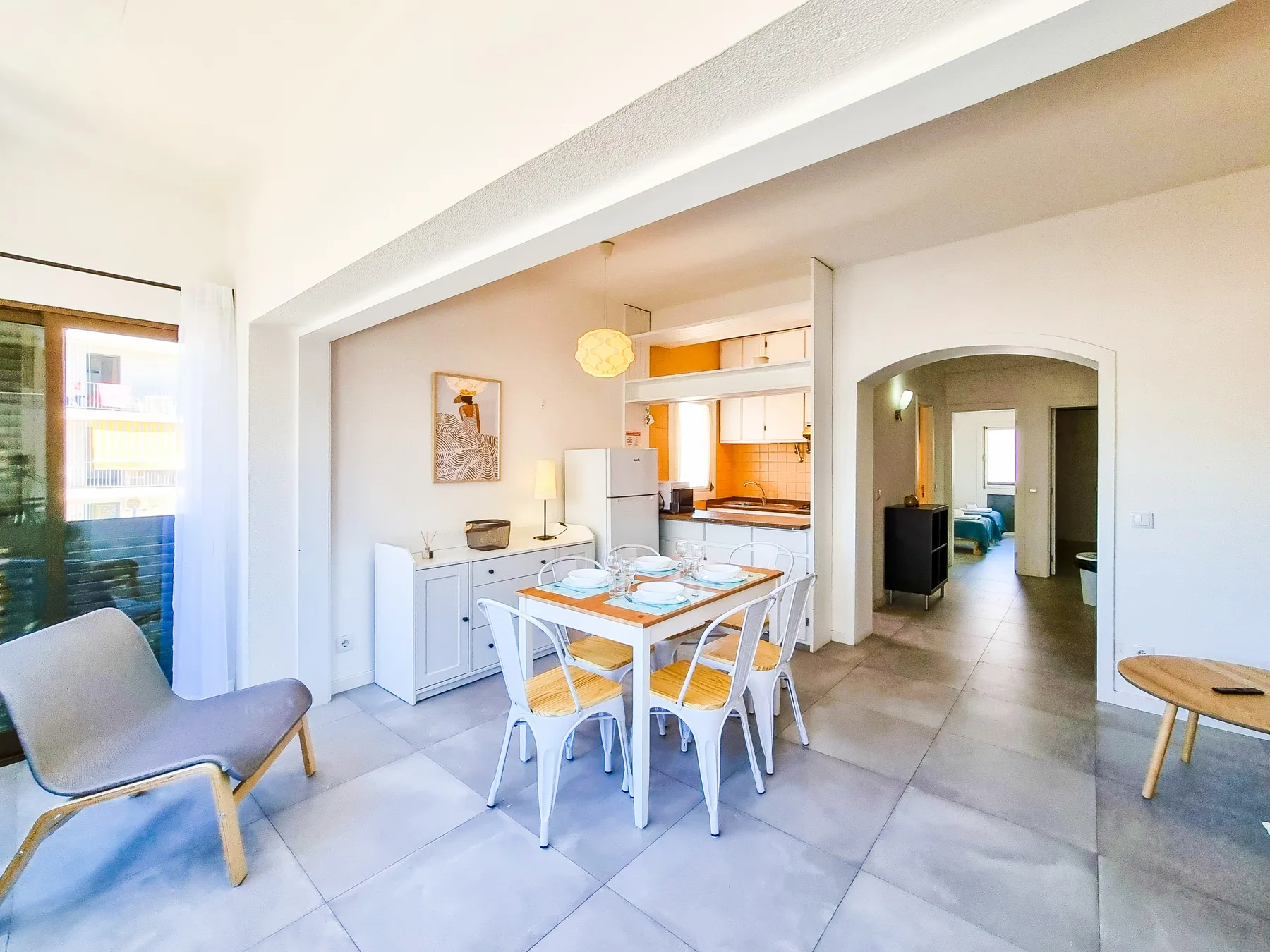 Un comedor luminoso se abre a una cocina compacta y una habitación contigua.