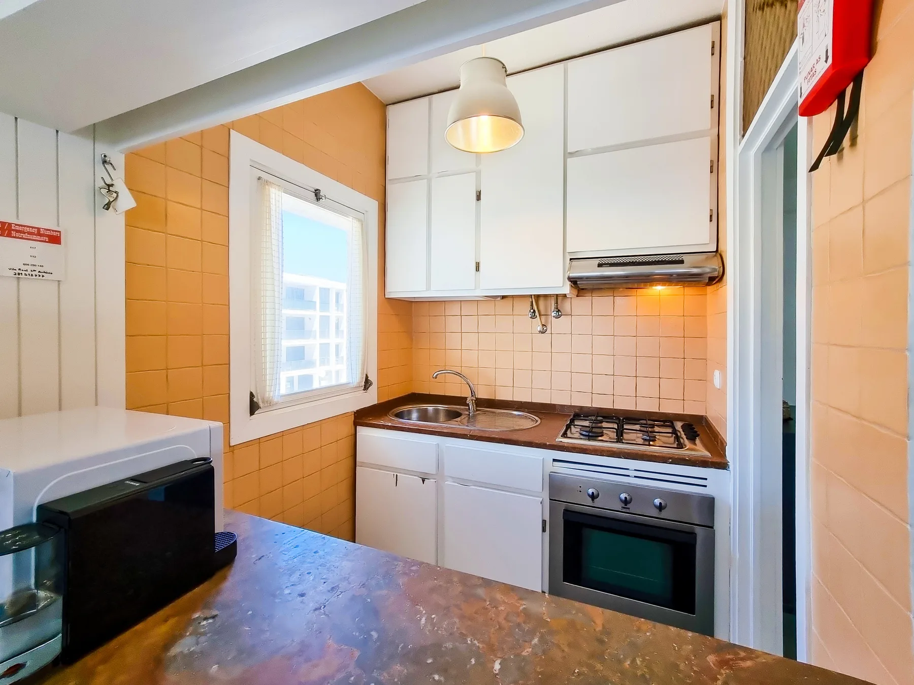 Una cocina compacta con armarios blancos, fregadero y cocina.