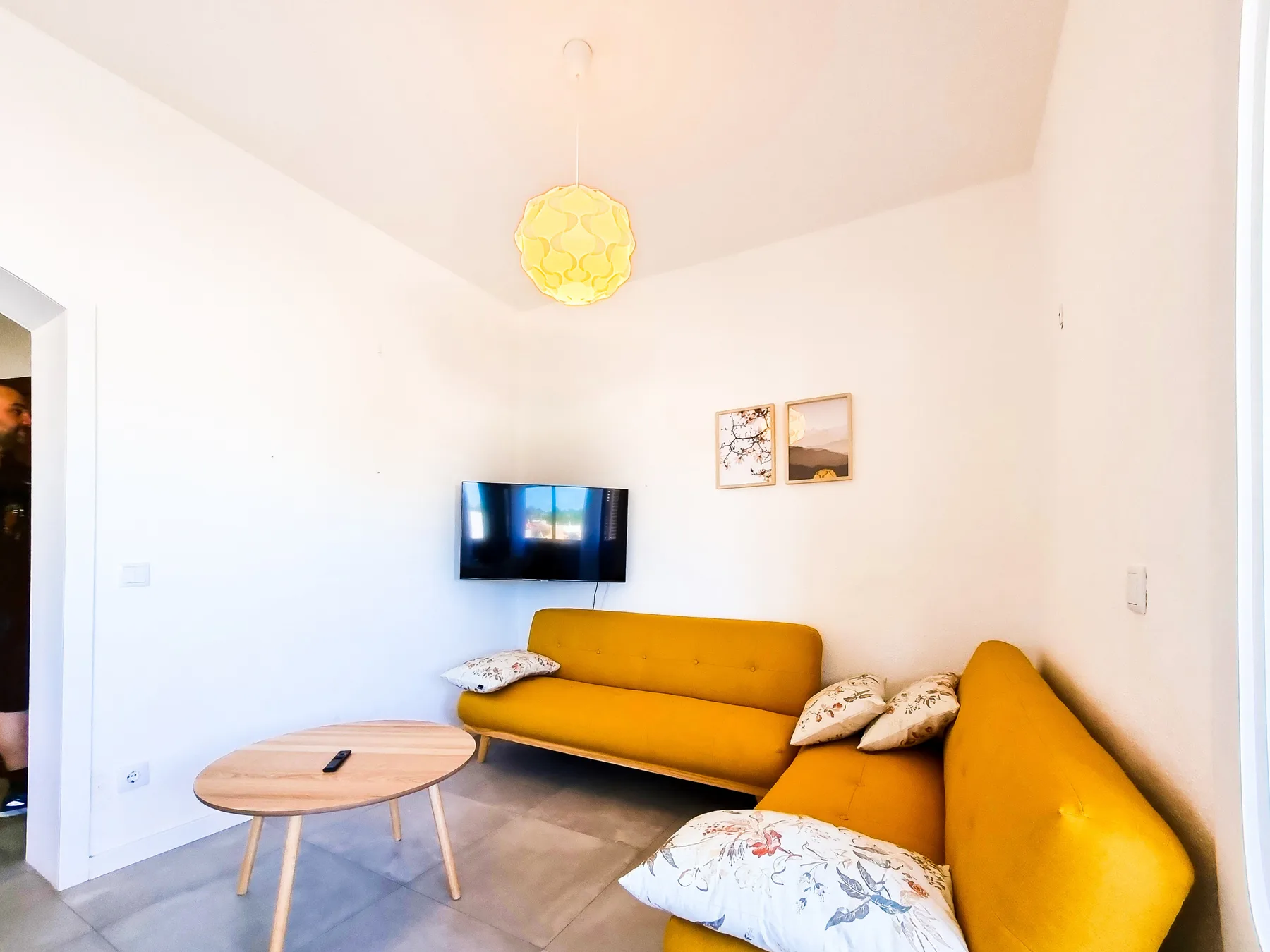 Sala de estar con asientos color mostaza y una mesa de centro redonda.