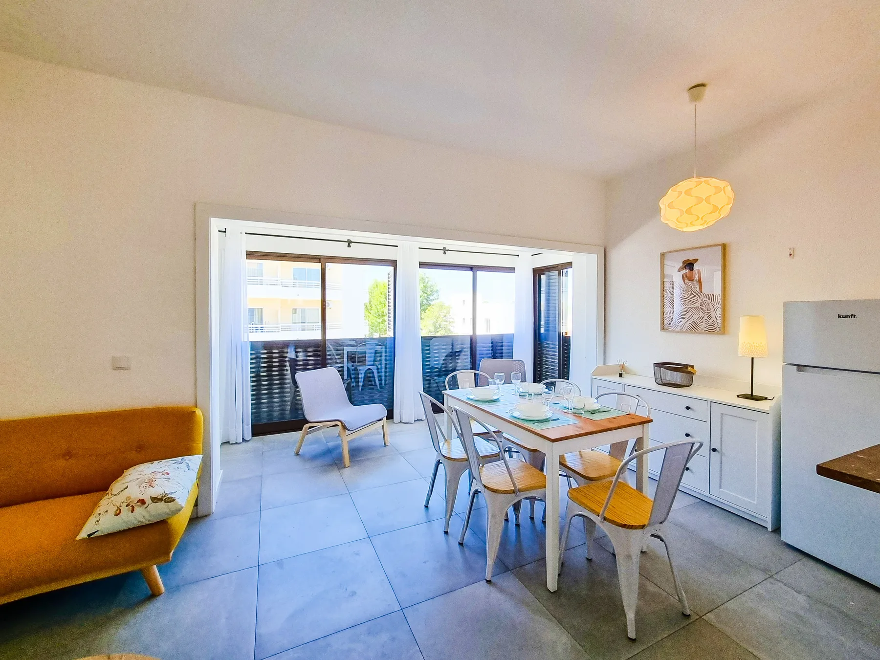 Un comedor luminoso con una mesa y asientos junto a grandes puertas de cristal.