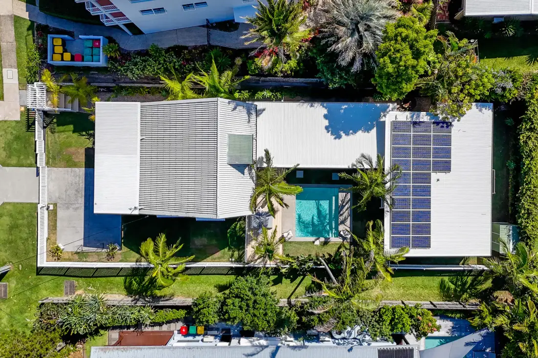 Una vista aérea muestra una casa con una piscina central y vegetación alrededor.
