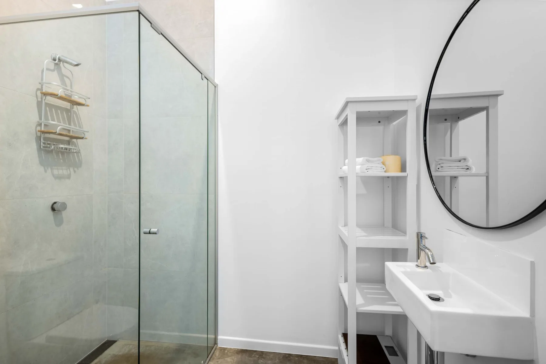 Un baño luminoso con una ducha de vidrio y un lavabo blanco.