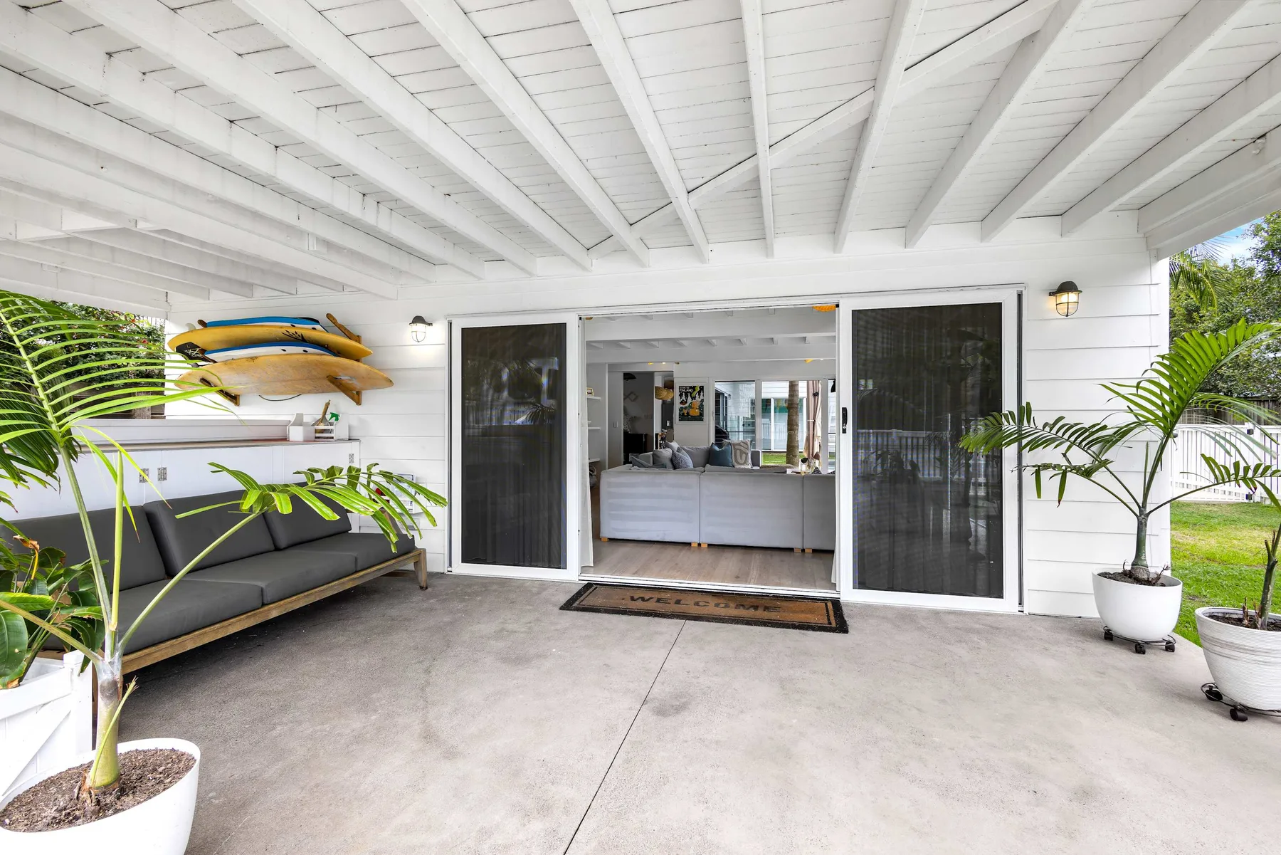 Un patio cubierto con asientos y puertas abiertas que dan al interior de la casa.