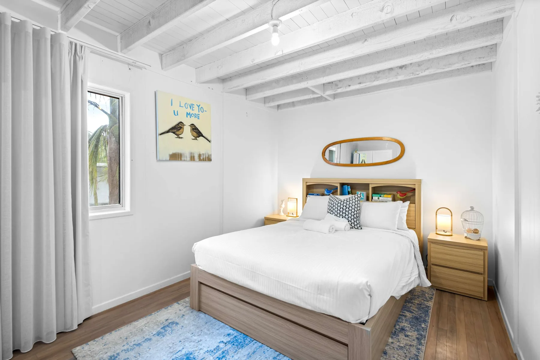 Un dormitorio luminoso con una cama bien tendida y una ventana al lado.