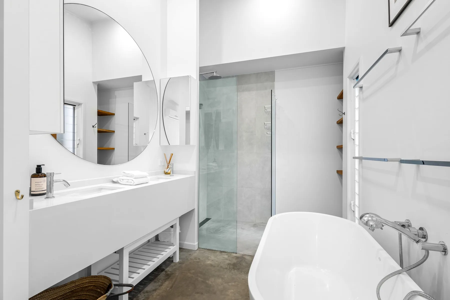 Un baño luminoso con bañera, ducha de vidrio y un tocador largo.