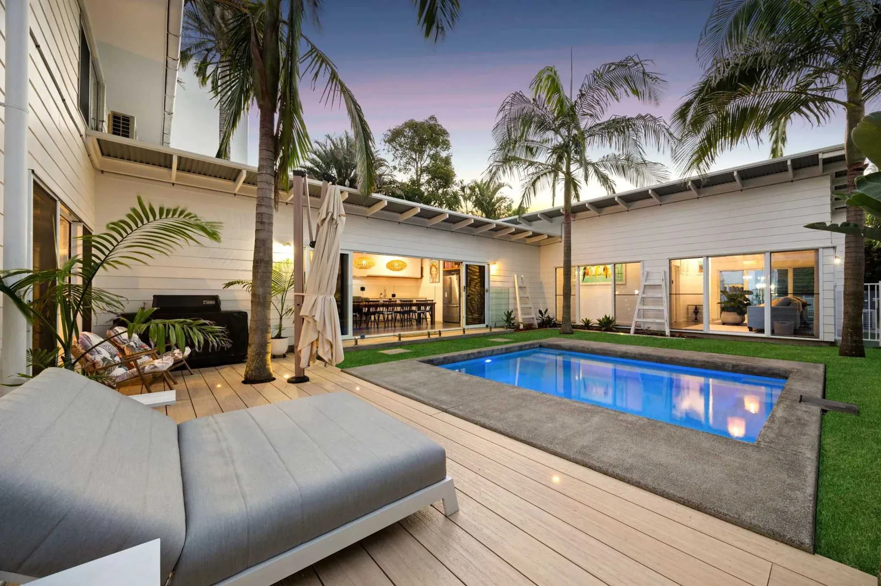 Un patio trasero da a una piscina junto a una casa moderna.