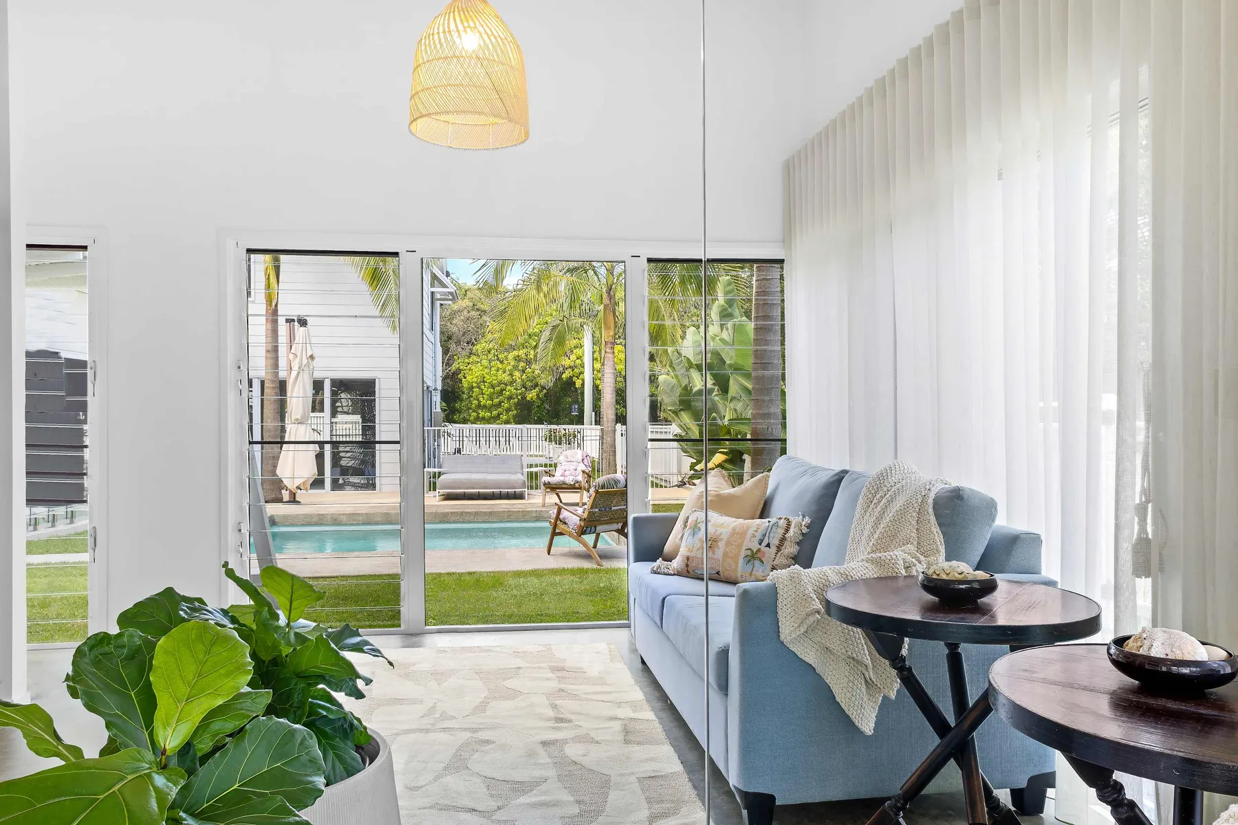 Una sala luminosa con asientos azules y puertas de vidrio que dan a un patio junto a la piscina.
