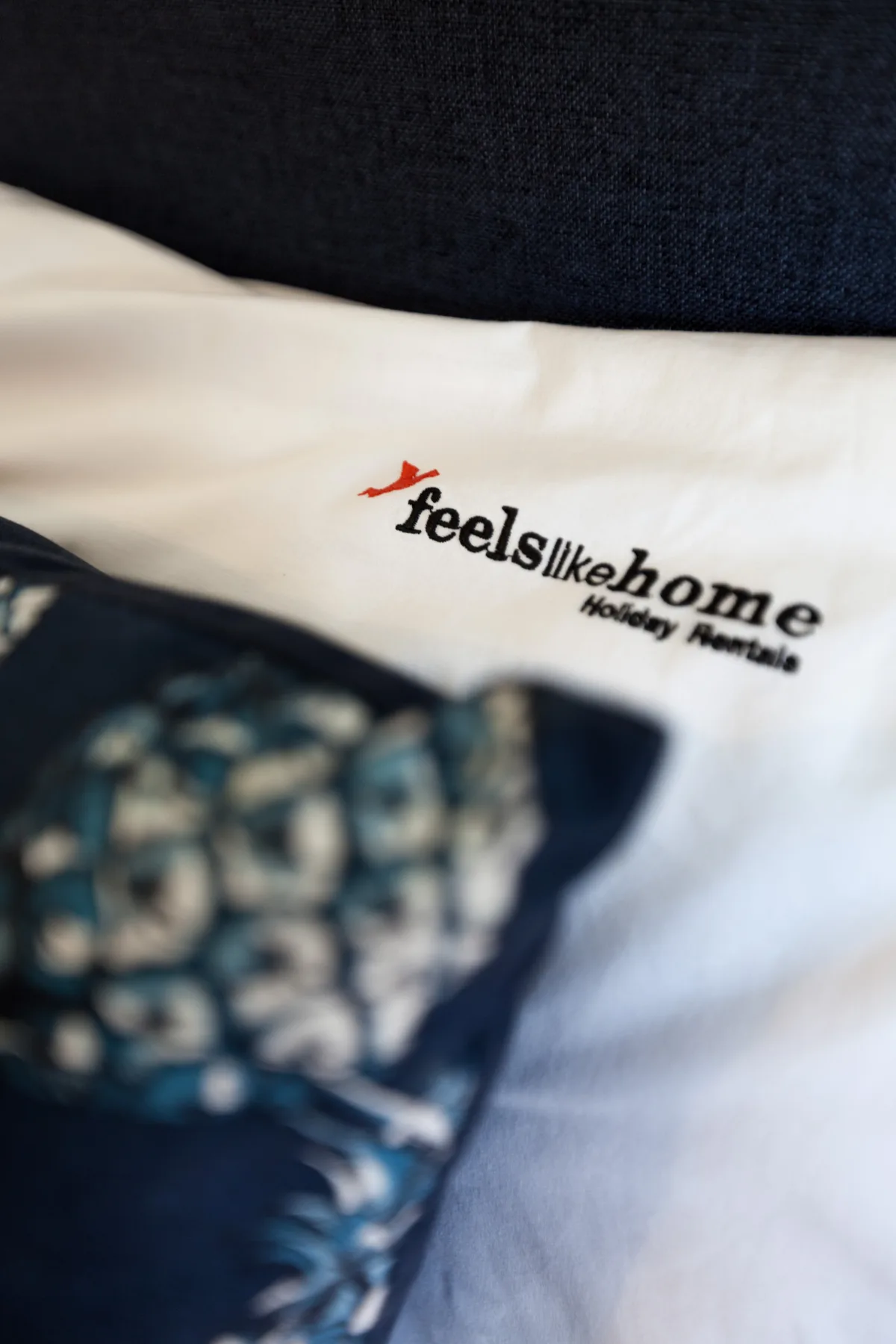 Una cama con ropa de cama blanca y un logotipo impreso junto a una tela estampada.