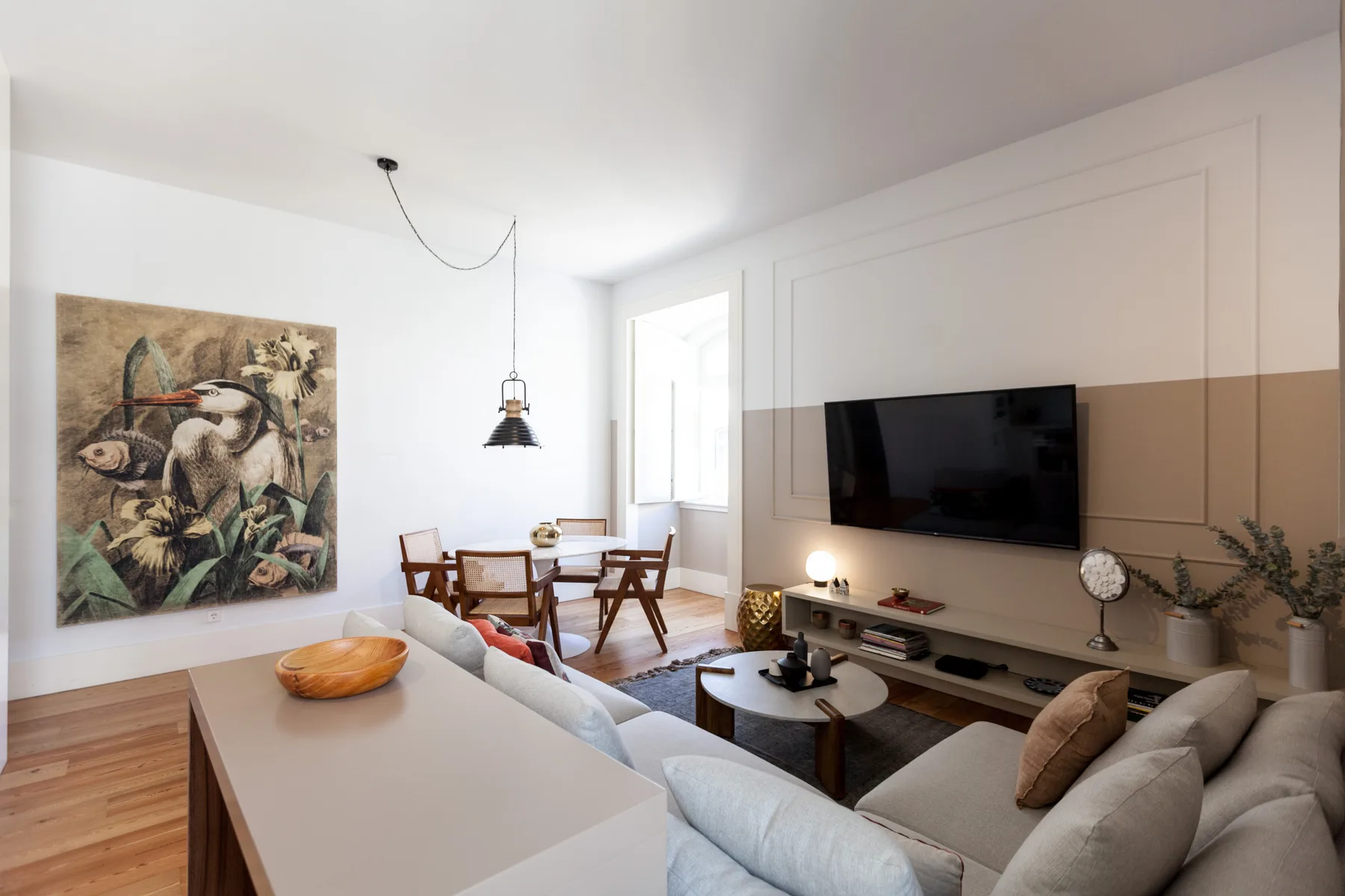 Una sala luminosa con asientos, un televisor y un comedor junto a la ventana.
