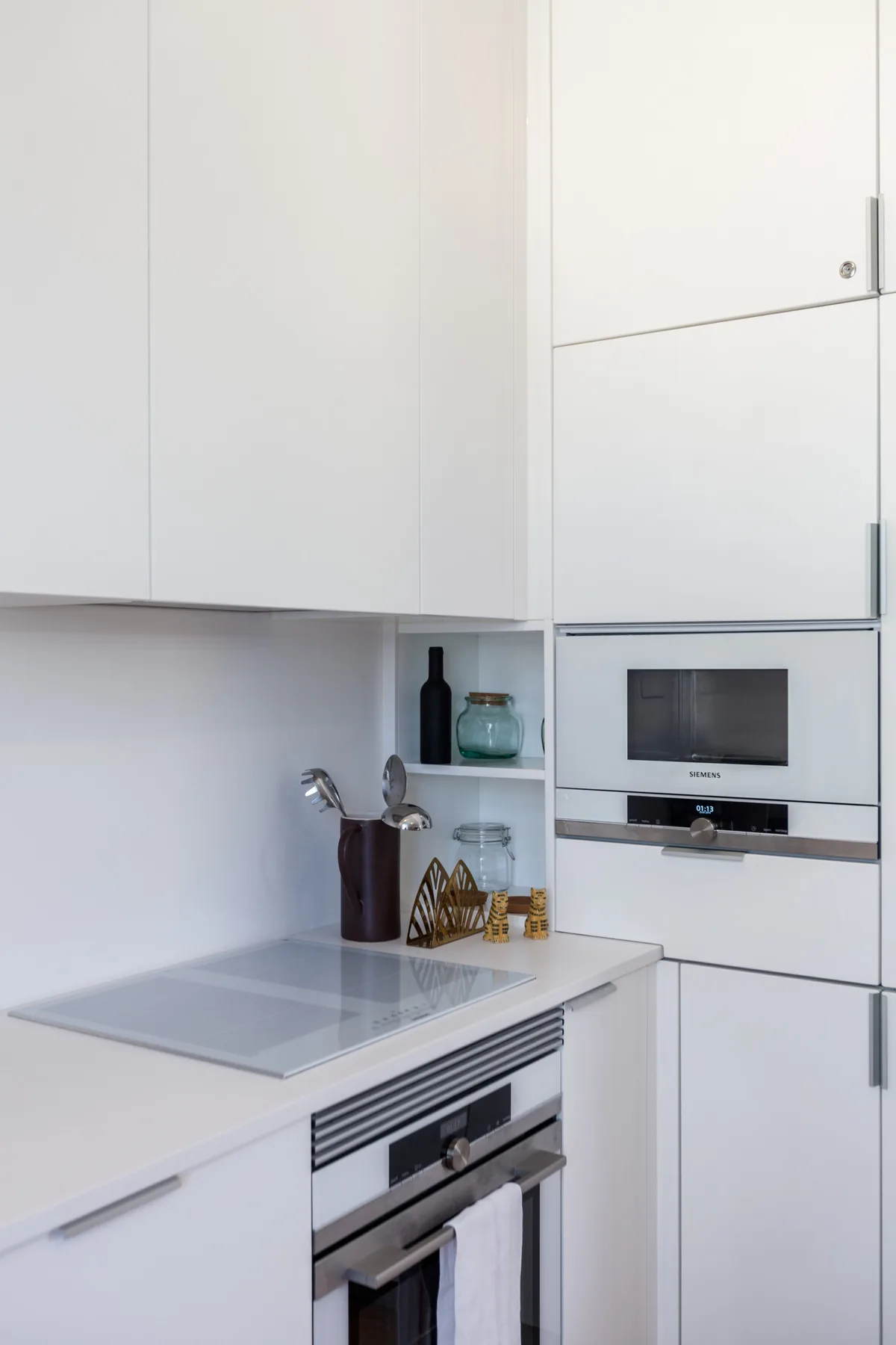 Una cocina blanca moderna con una placa de cocción y un horno empotrado.