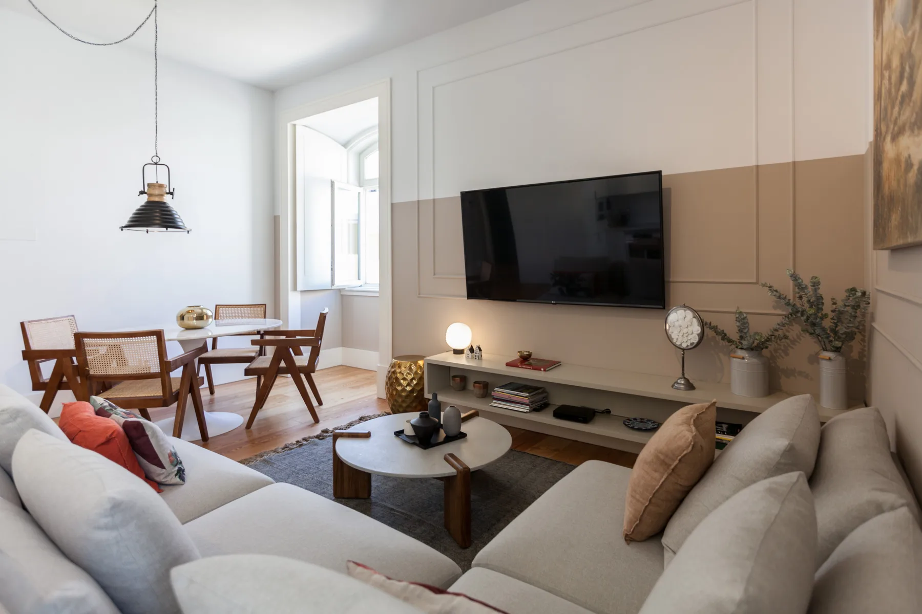 Una sala de estar luminosa con asientos, un televisor y una mesa de comedor.