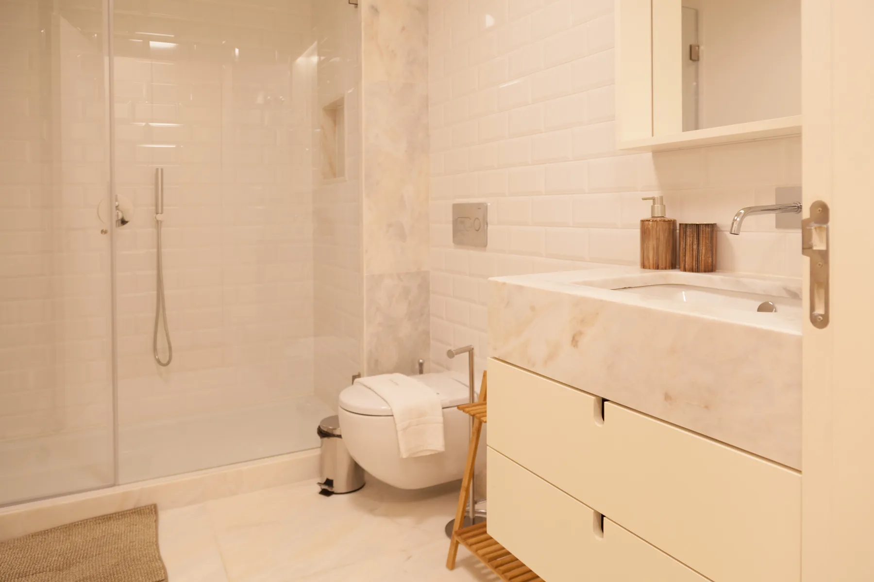 Un baño luminoso con ducha de cristal, inodoro y lavabo con mueble.