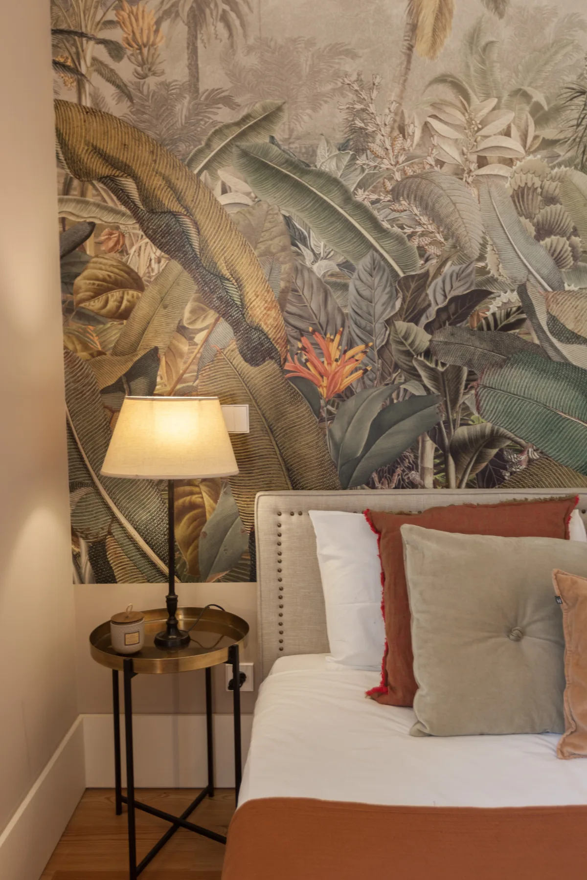 Un dormitorio con una cama junto a una lámpara y un mural botánico.