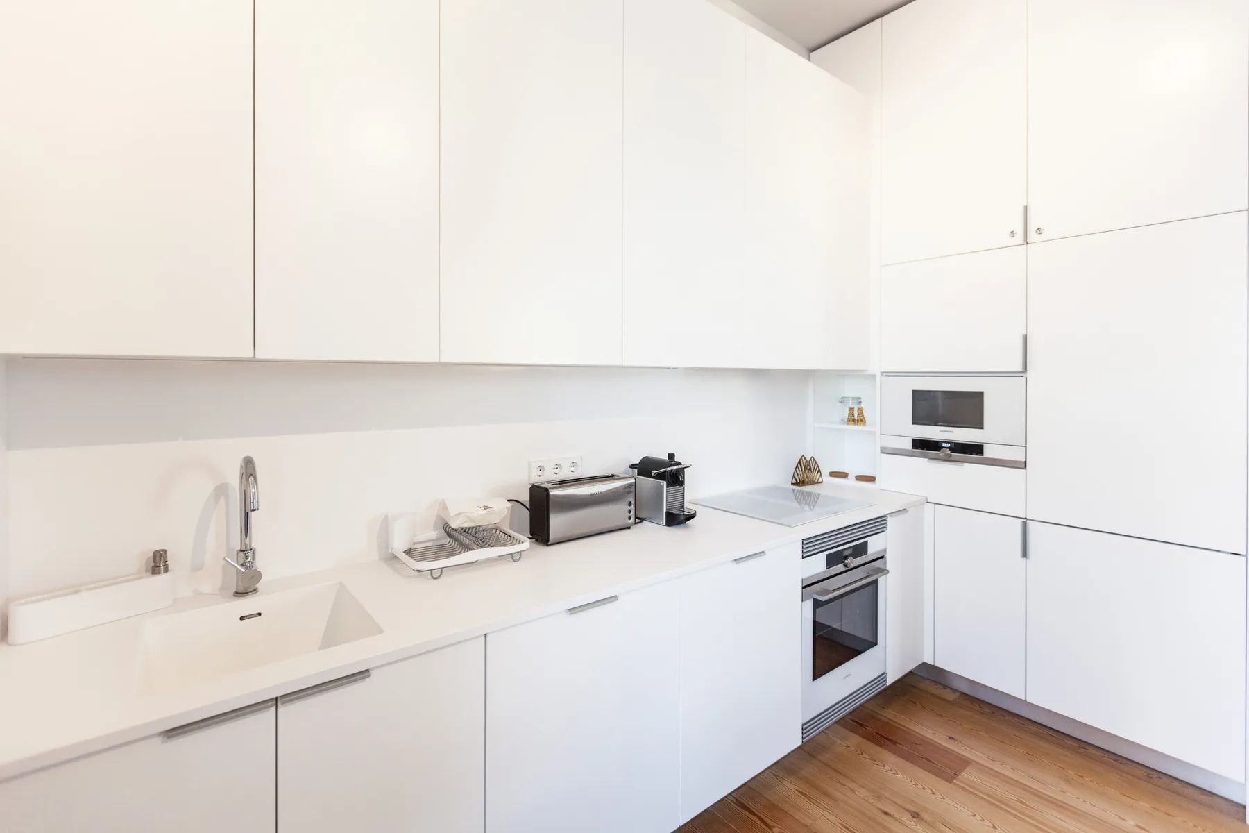 Una cocina moderna y luminosa con gabinetes blancos, una encimera y electrodomésticos empotrados.